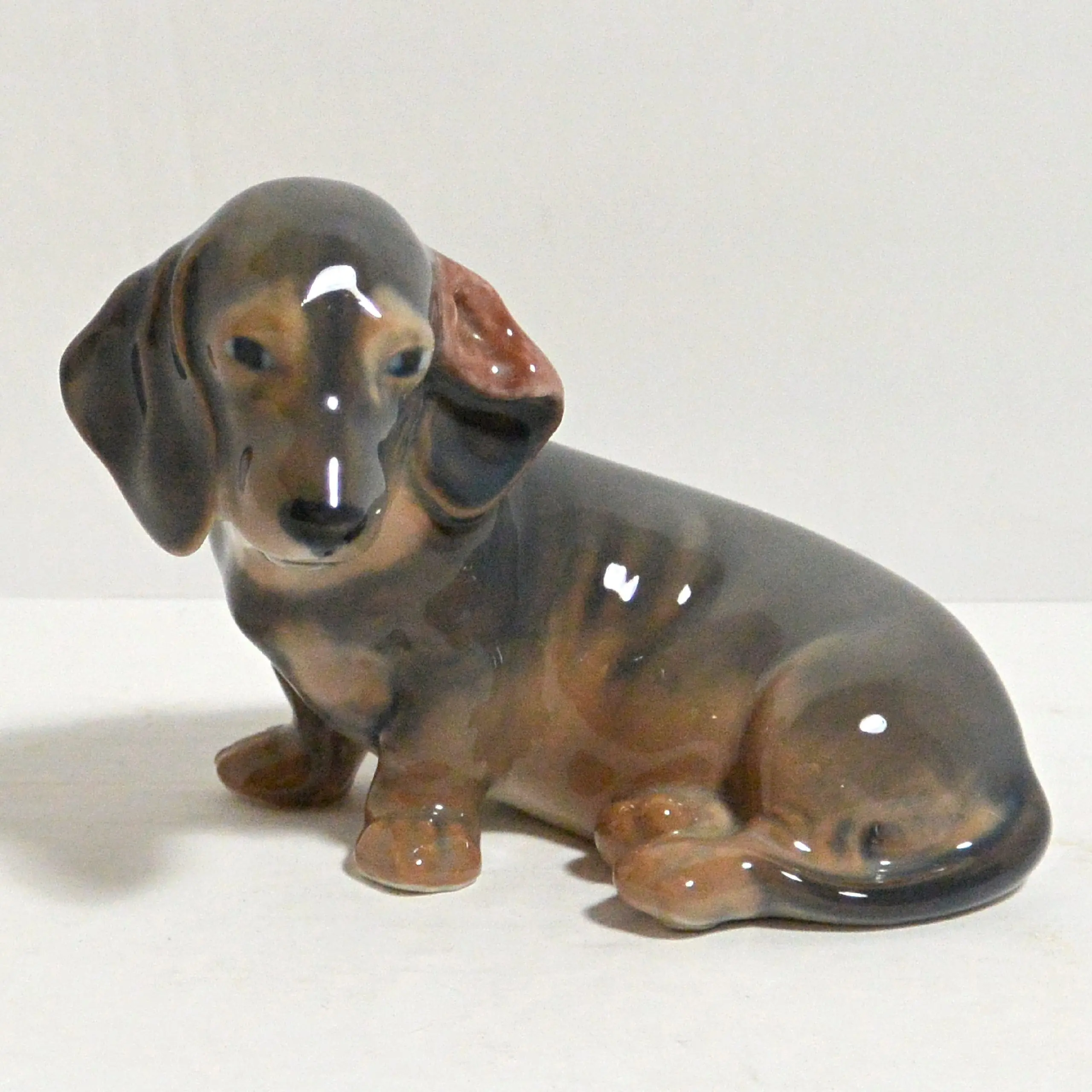 Royal Copenhagen Dachshund porcelain figurine circa 1923-1928, seated pose with hand-painted brown underglaze